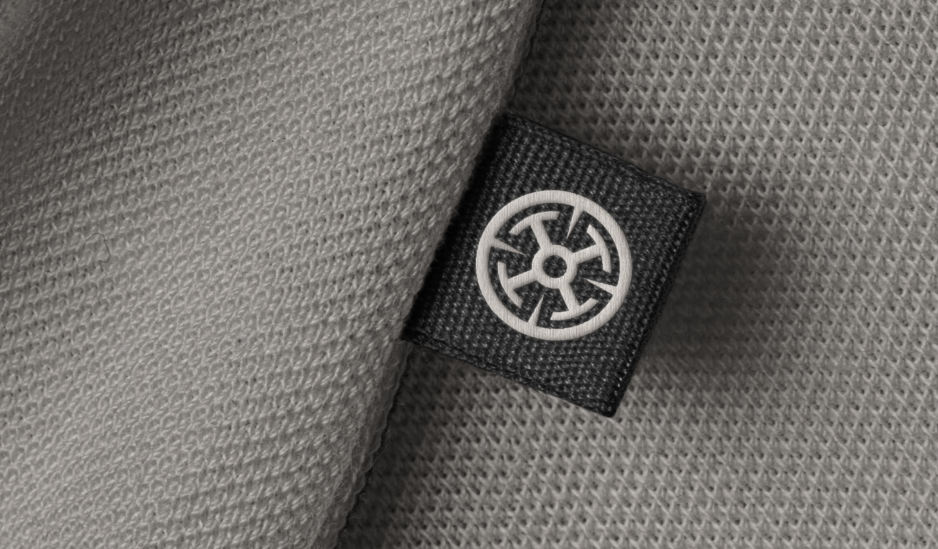 The ROTA wheel woven into a garment tag — a modern talisman carried close to the body